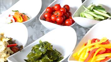 A variety of food items in white bowls on a table with ice.