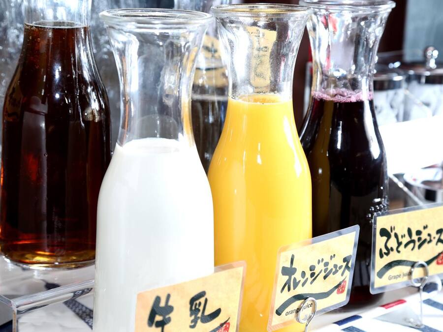 Variedad de bebidas en botellas de vidrio con etiquetas, incluyendo una bebida blanca, una anaranjada y una de color oscuro, probablemente en un bar o restaurante.