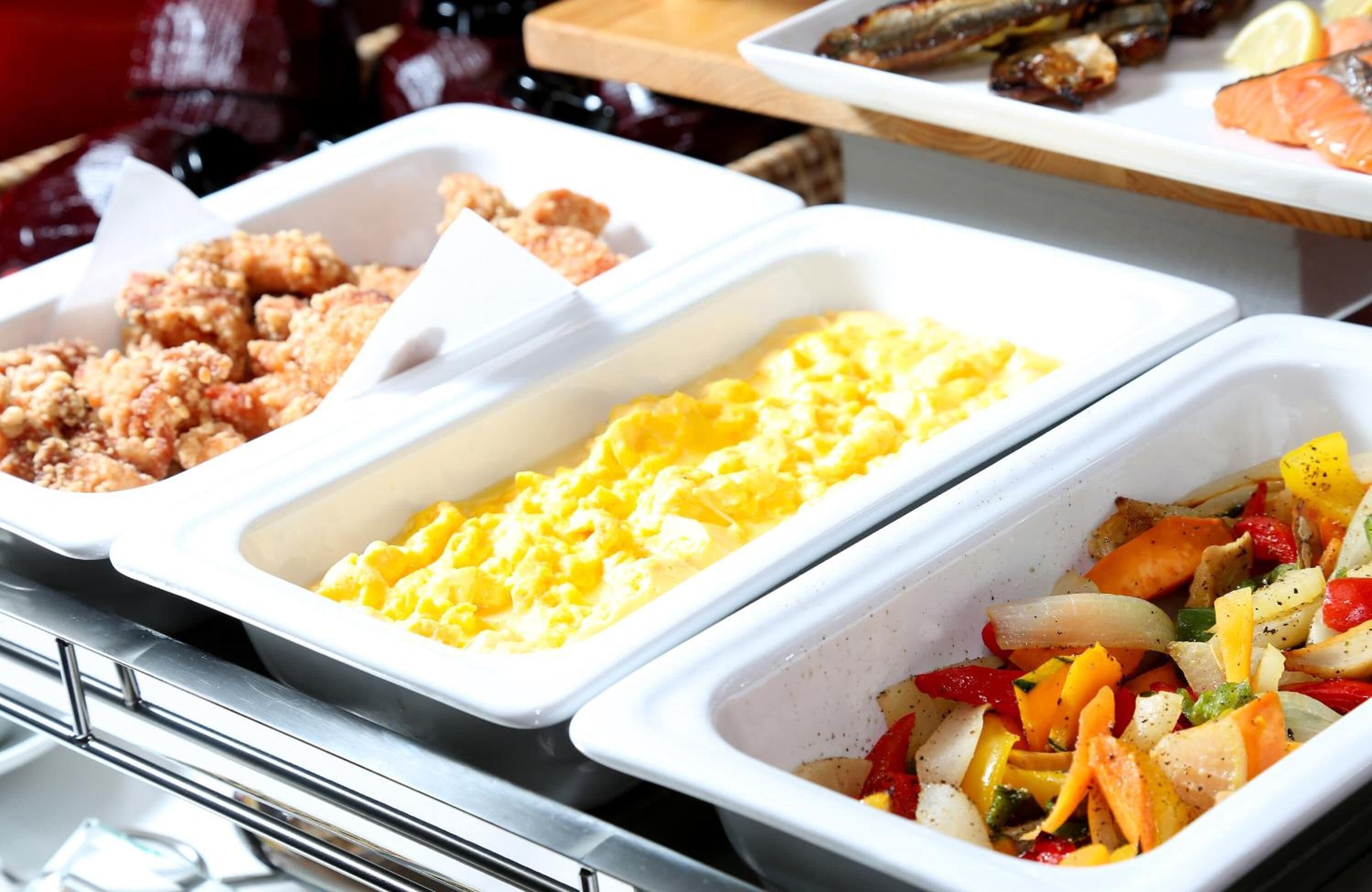 A buffet with various food options including fried chicken, scrambled eggs, and a vegetable stir-fry.