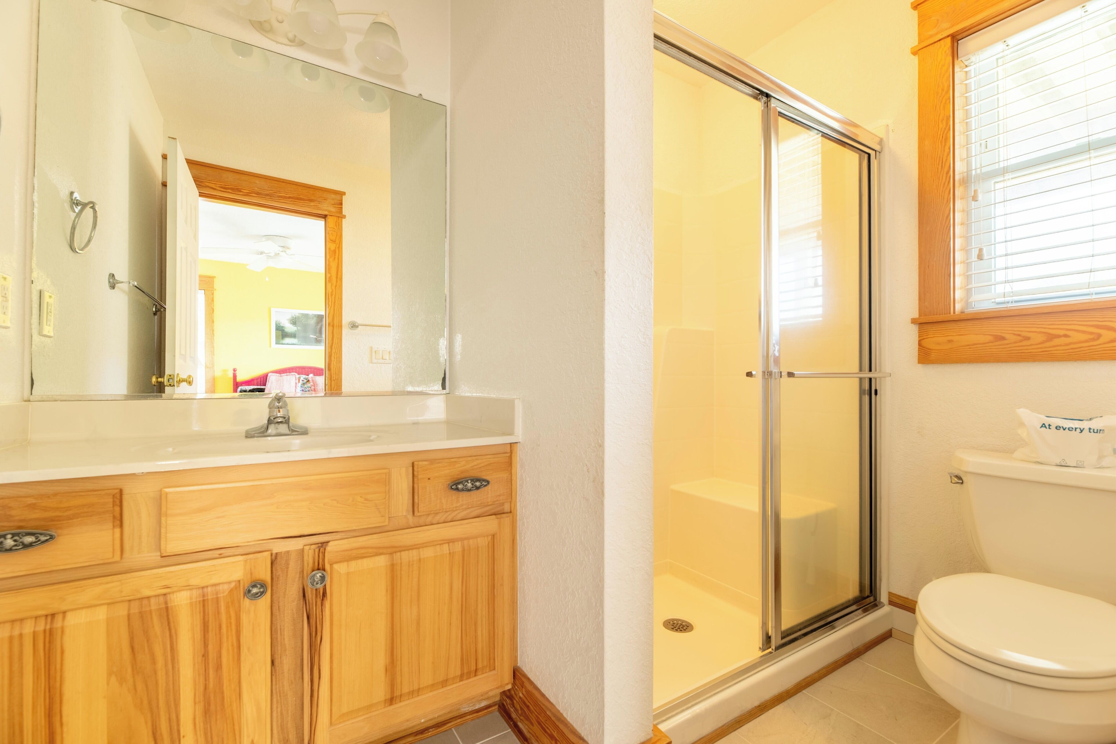 Une salle de bain avec un meuble-lavabo en bois, une cabine de douche en verre et des toilettes.