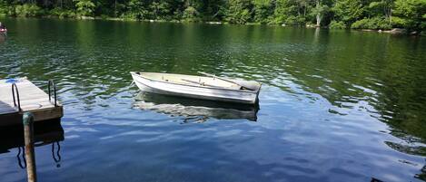 Un petit bateau était amarré à un quai en bois, avec une côte boisée en arrière-plan.