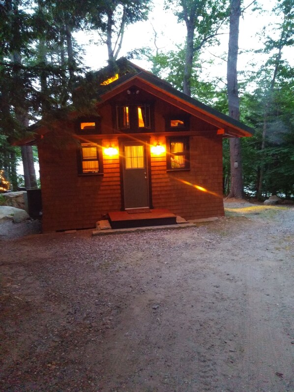 A small wooden cabin with a front porch, a door, and windows.