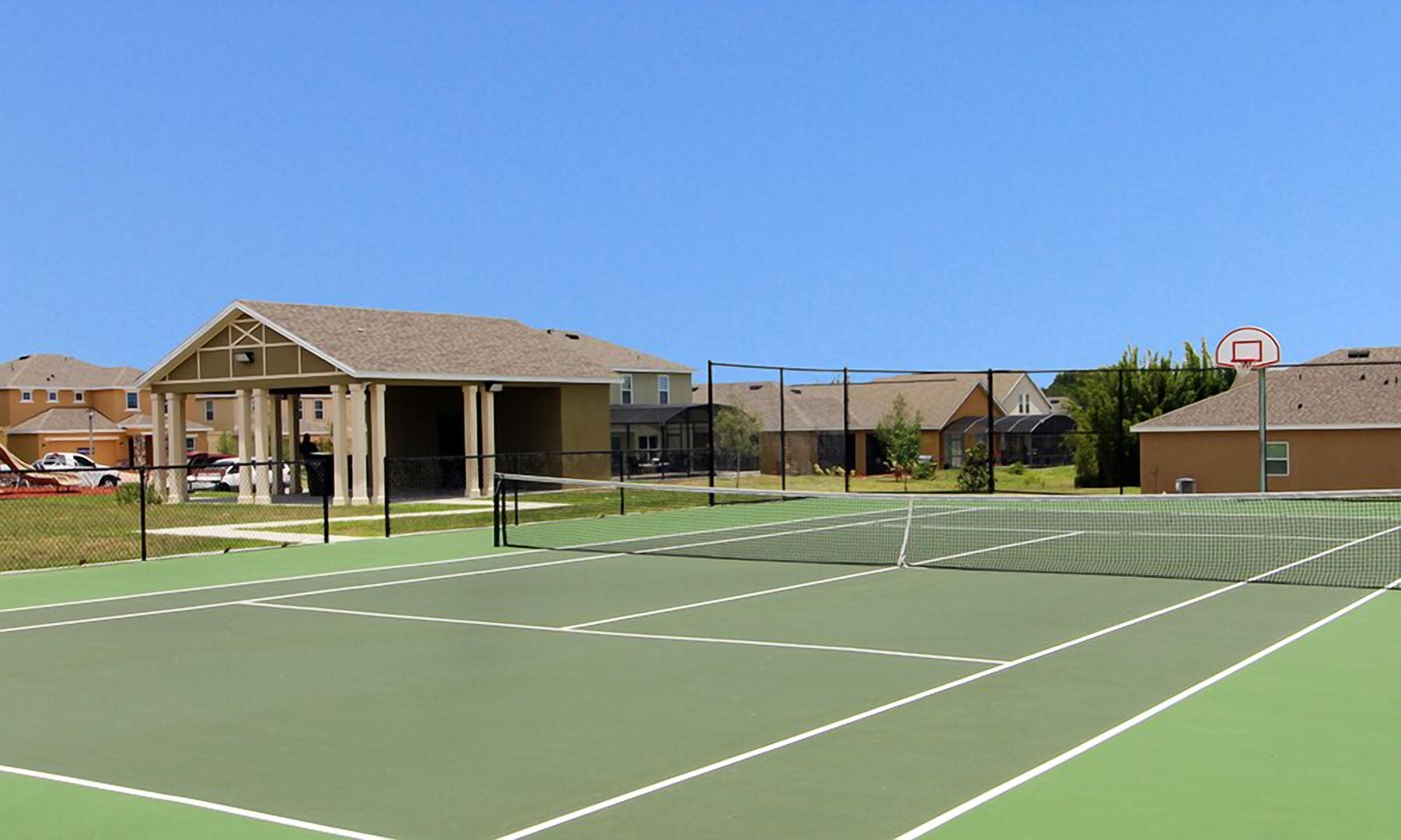 Una cancha de tenis con red, rodeada de edificios residenciales.