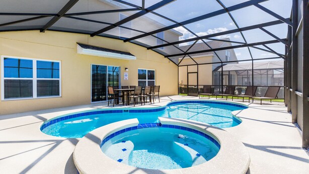 Ein überdachter Poolbereich im Freien mit Whirlpool, Sitzgelegenheiten und einer Terrasse.