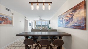 Un espace repas comprenant une longue table, six chaises et un lustre moderne.