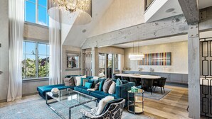 A spacious living area with a large sofa, a coffee table, and a dining table in the background.