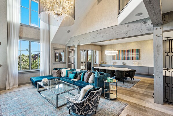 A spacious living area with a large sofa, a coffee table, and a dining table in the background.