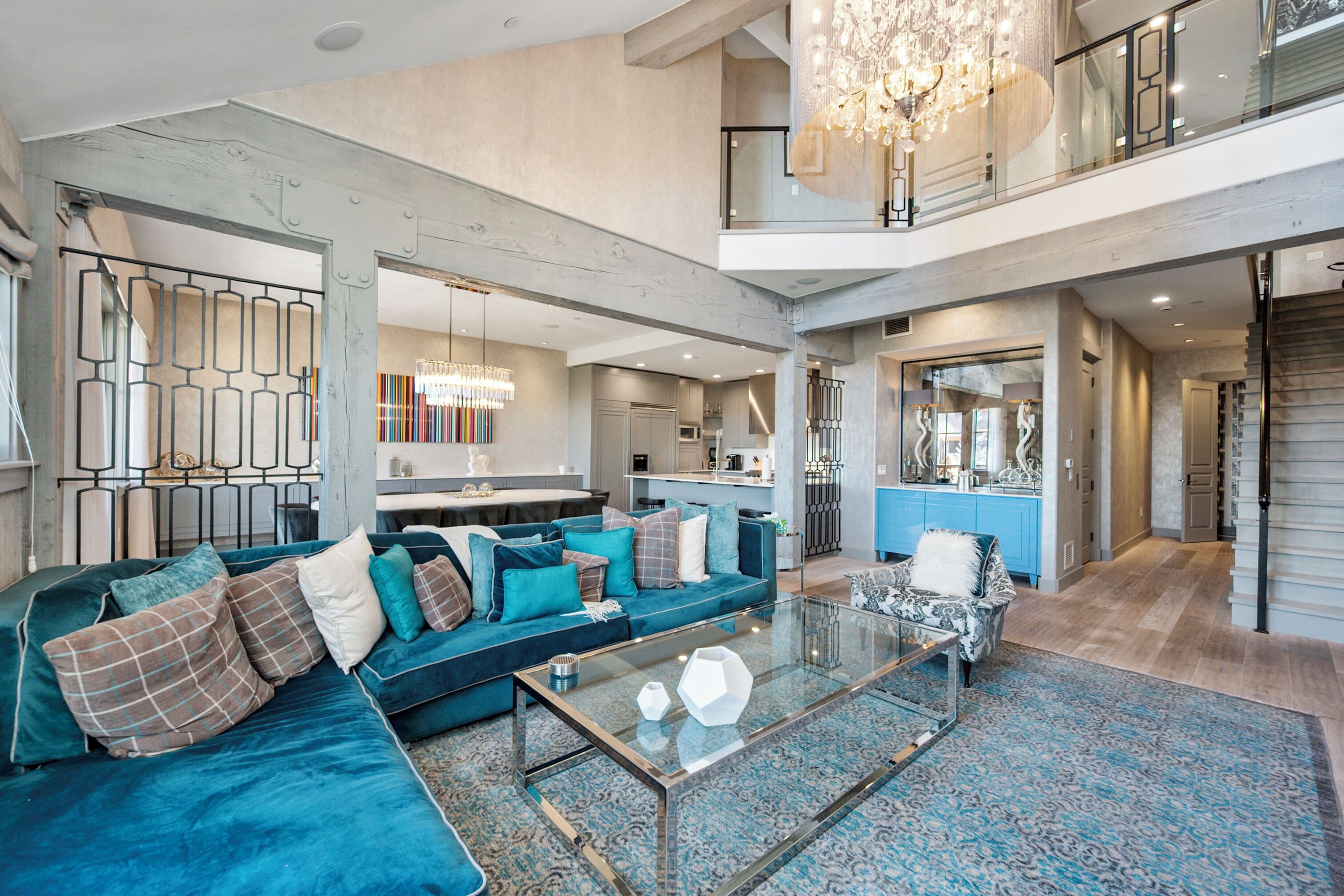 A spacious living area with a large sofa, a glass coffee table, and a chandelier.