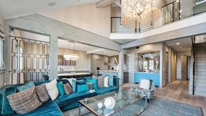 A spacious living area with a large sofa, a glass coffee table, and a chandelier.