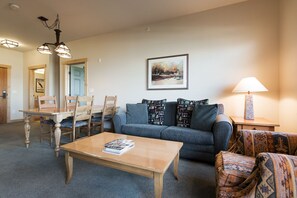 A living room with a sofa, coffee table, and chairs. There is a painting on the wall and a lamp on a side table. - Ski-in, Ski-out Condo at Juniper Springs with Mountain Views and Shared Hot Tub! (Mammoth Lakes)