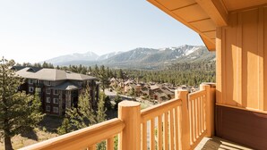Un balcón de madera con vistas a una cadena montañosa y una zona residencial.