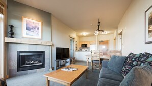 Una sala de estar con chimenea, sofá, mesa de centro y televisor.
