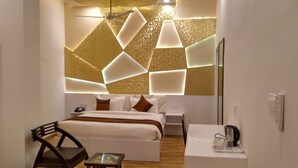A modern hotel room with a bed, bedside table, chair, and a small table with a kettle and cups. - Sallow Royal Suites (Amritsar)