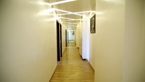 A hallway with wooden flooring and white walls. - Sallow Royal Suites (Amritsar)