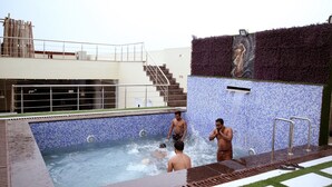 A swimming pool with a tiled edge, a staircase, and a mural on the wall. - Sallow Royal Suites (Amritsar)
