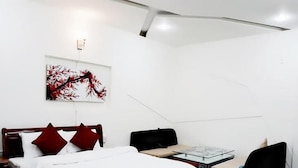 A hotel room with a bed, a desk, and a chair. There is a painting on the wall. - Snooze Hotel (Hue)