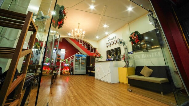 A hotel lobby with a reception desk, a staircase, and a sofa. - Snooze Hotel (Hue)