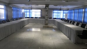Ett konferensrum med långa bord, stolar och takfläktar.