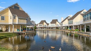 Une rangée de maisons au bord de l’eau, avec un étang au premier plan.