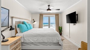 Une chambre à coucher comprenant un lit, un bureau, une chaise, un téléviseur et une fenêtre donnant sur un beau paysage.