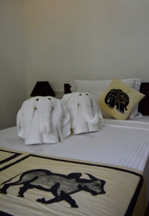 Un lit avec deux serviettes blanches en forme d’éléphant et un oreiller orné d’un motif d’éléphant.