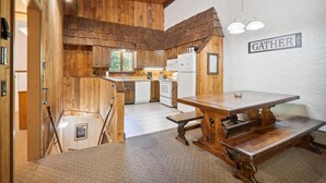 A rustic kitchen with wooden walls, a stone fireplace, and a dining area with benches. - Cozy 4-Bedroom Townhouse– Ideal for Groups & Families Snow Flake (Killington)