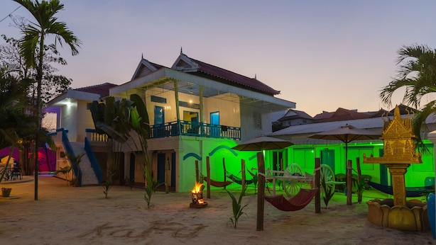 Une propriété située en bord de mer, comprenant une grande maison, un hamac et un élément décoratif aquatique.