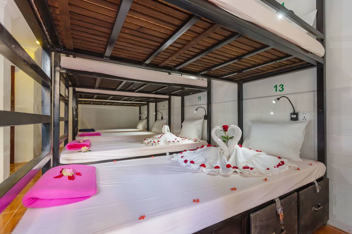 Habitación de hotel con literas, un cartel con el número 13 y un espejo que refleja la habitación.