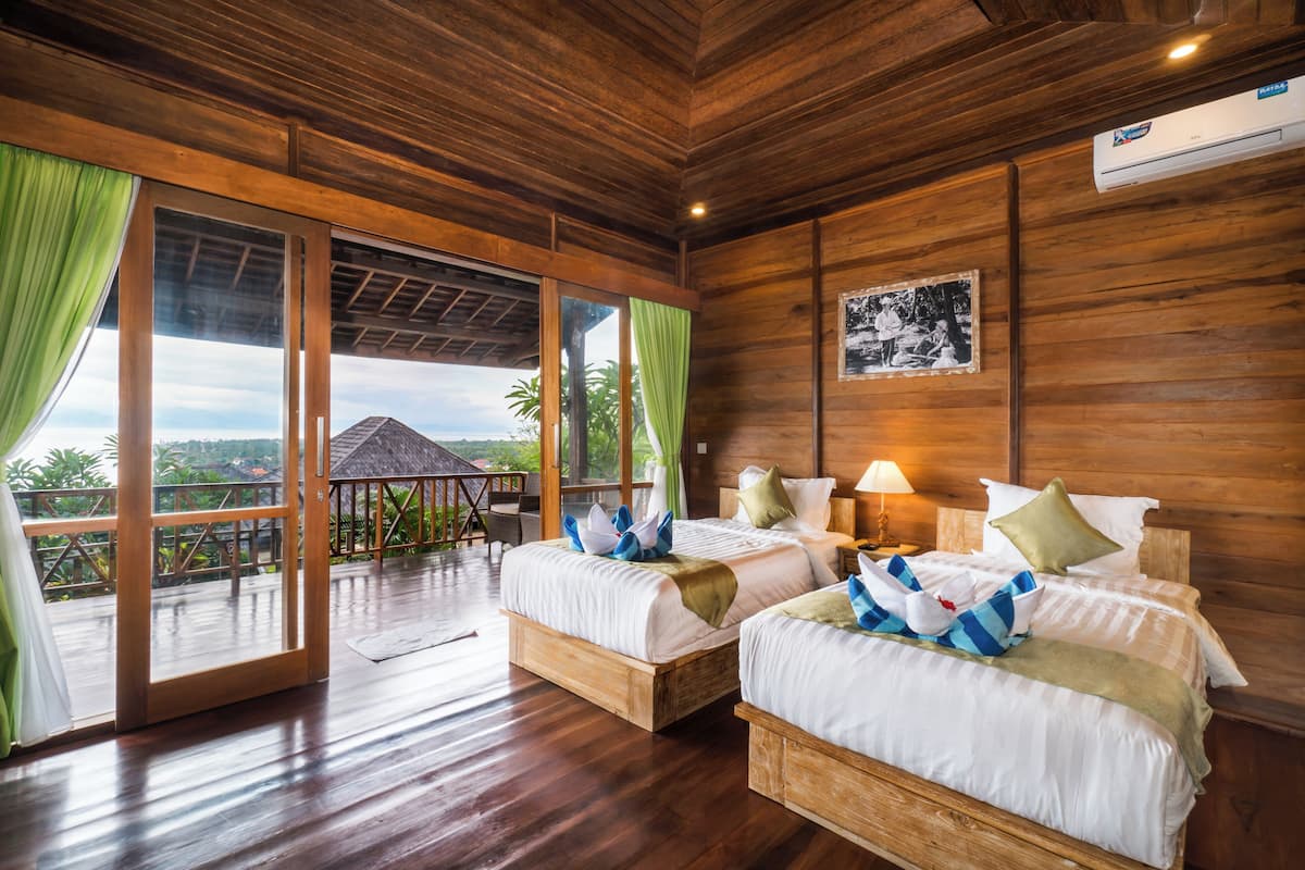A wooden room with two beds, a ceiling fan, and a view of the outdoors.