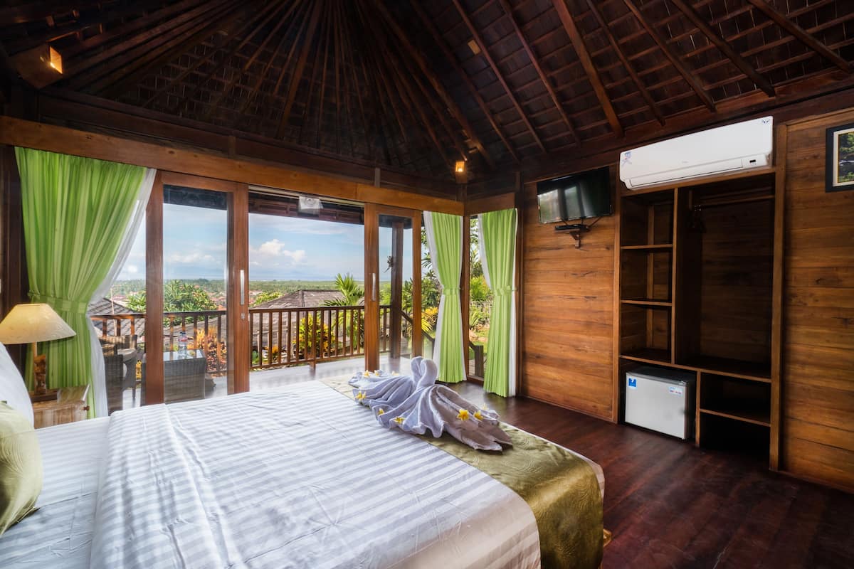 A bedroom with a bed, curtains, a TV, and a small refrigerator.