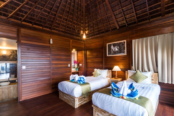 Een houten kamer met twee bedden, een nachtkastje, een lamp en een lijst aan de muur.