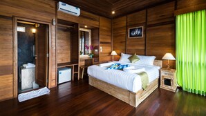 A wooden room with a bed, bedside tables, a desk, and an air conditioning unit. - Jenggala Hill (Lembongan Island)