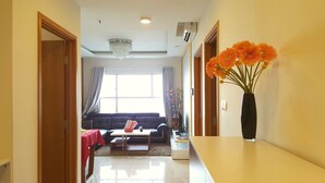 A modern living room with a sofa, coffee table, and a vase of flowers. - Sunrise City 2BR Luxury SWPool 30th (Ho Chi Minh City)