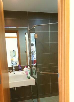 A bathroom with a mirror, sink, and dark tiled walls. - Sunrise City 2BR Luxury SWPool 30th (Ho Chi Minh City)