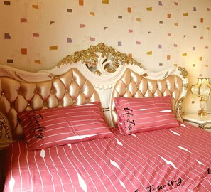 A bed with a tufted headboard, two red striped pillows, and a bedside table with a lamp. - Sunrise City 2BR Luxury SWPool 30th (Ho Chi Minh City)