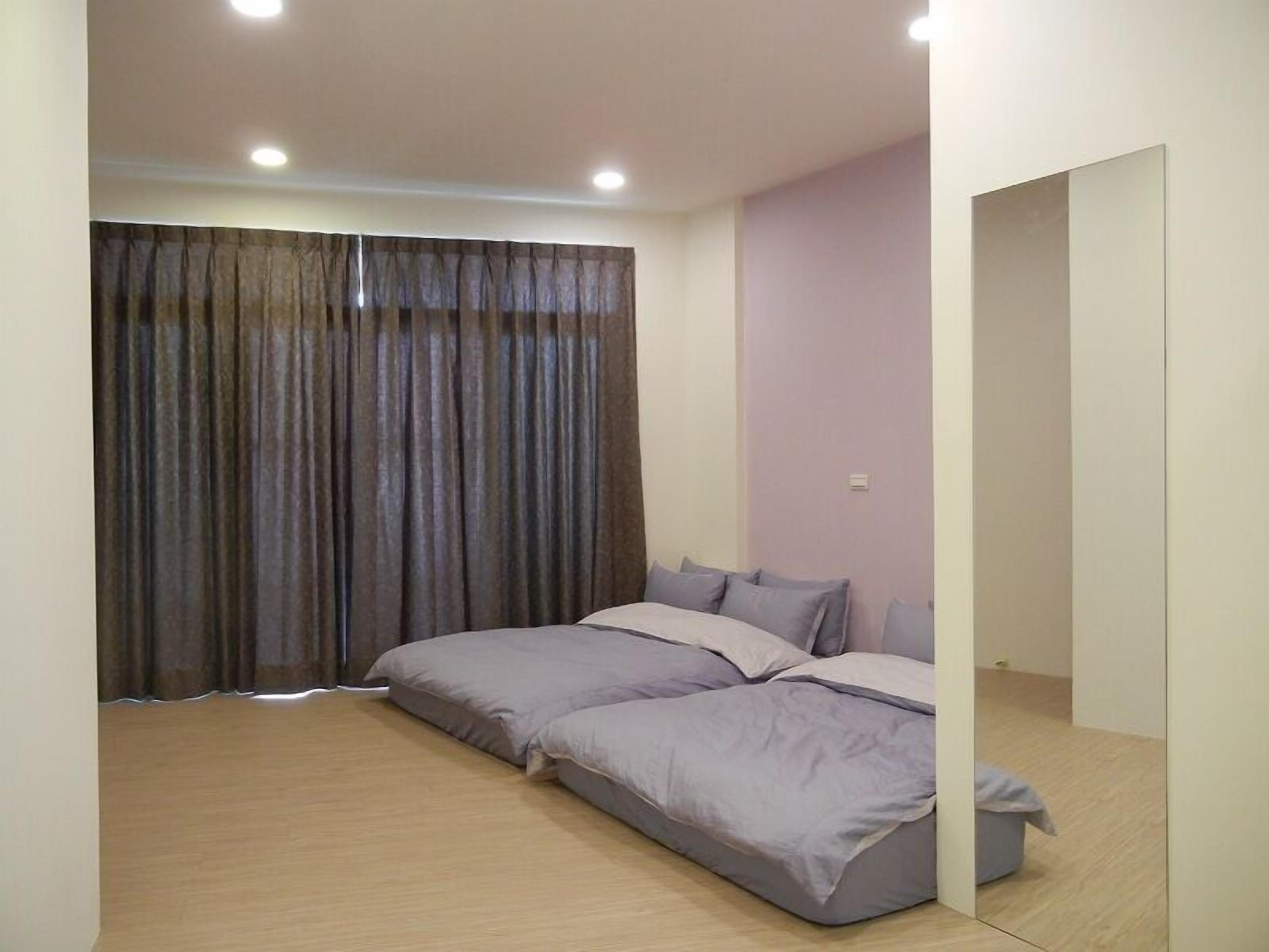 A modern bedroom with a large bed, a wardrobe, and a mirror.