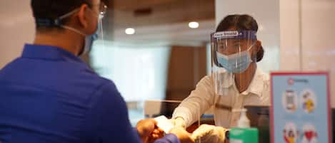 A person wearing a face shield and a mask at a counter, likely in a service or retail setting.