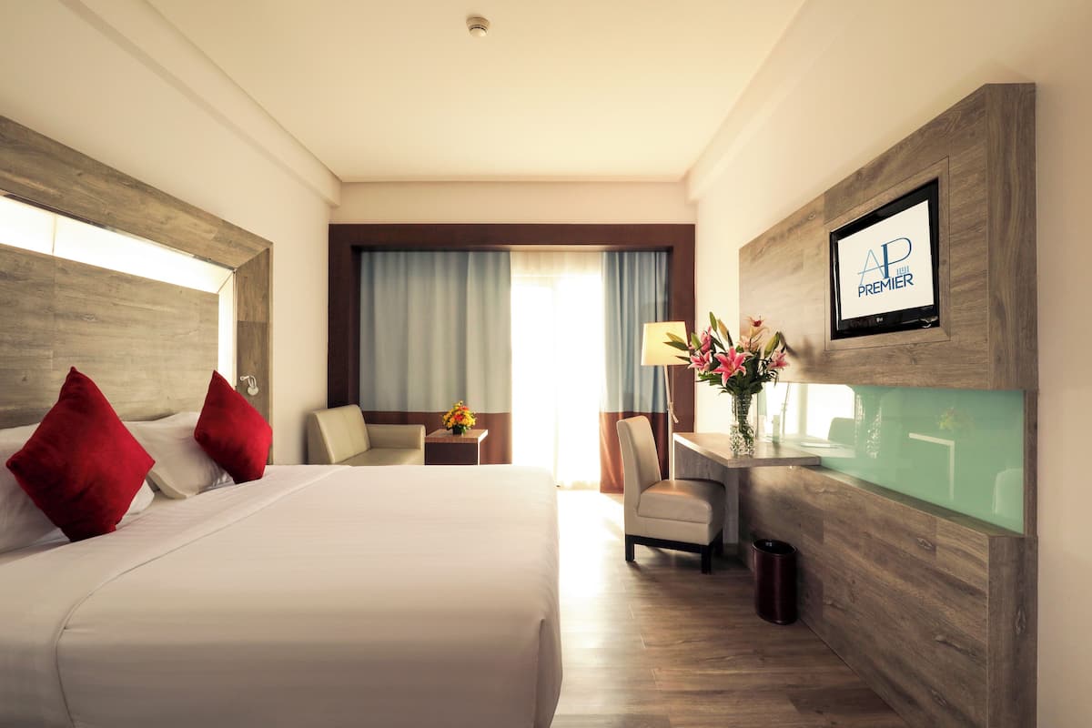 A hotel room with a large bed, a desk with a computer, and a TV on the wall.