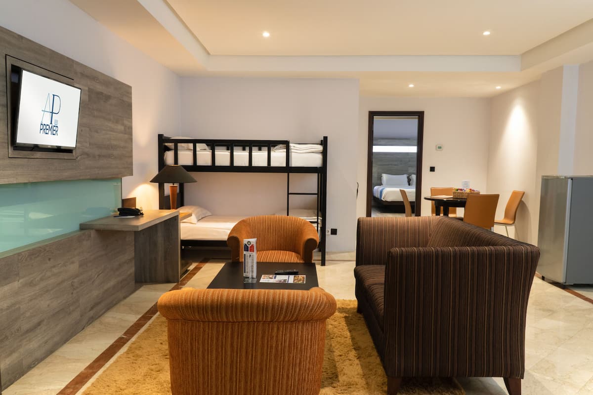 A hotel room with a bunk bed, a sofa, a coffee table, and a TV mounted on the wall.