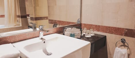 Un baño con lavamanos blanco, un espejo y un perchero para toallas.