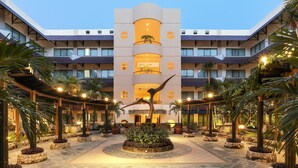 A modern hotel with a central atrium, multiple balconies, and a courtyard with potted plants and a unique tree sculpture. - AP Premier Batam (Batam)