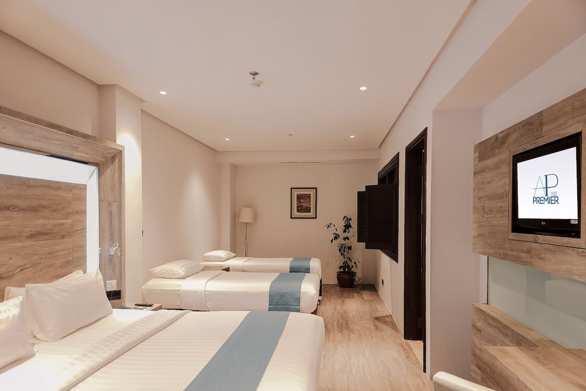 A hotel room with two beds, a TV, a lamp, and a potted plant.