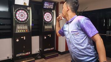 A man in a patterned shirt standing in front of two dartboards labeled "DartsLive 2".
