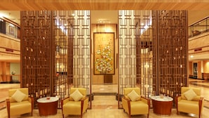A lobby with a reception desk, a decorative wall with a floral design, and seating area with chairs and a round table. - AP Premier Batam (Batam)