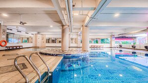 An indoor swimming pool with clear water, tiled floor, and metal handrails. - AP Premier Batam (Batam)