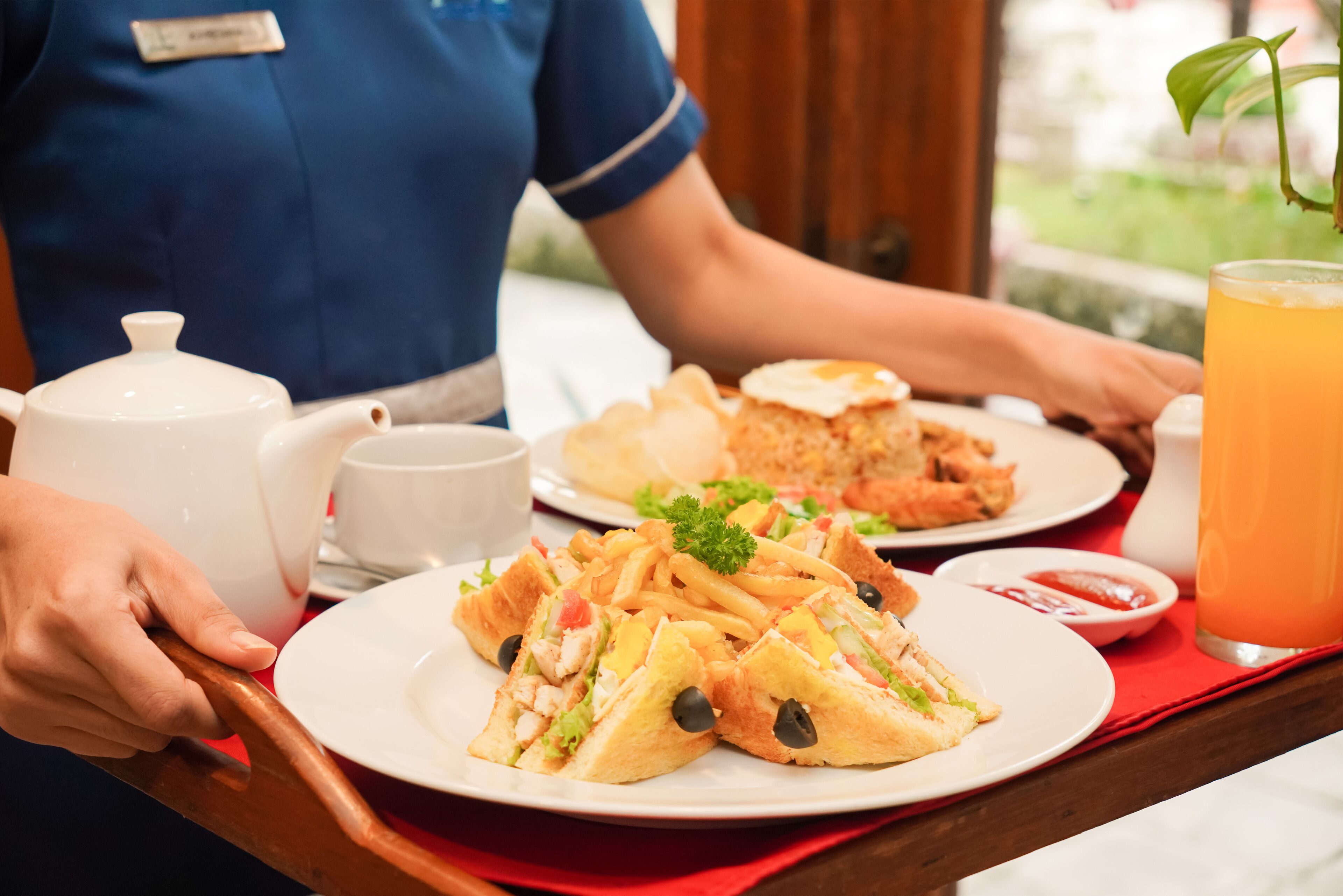 A tray with a sandwich, fries, a drink, and a teapot.