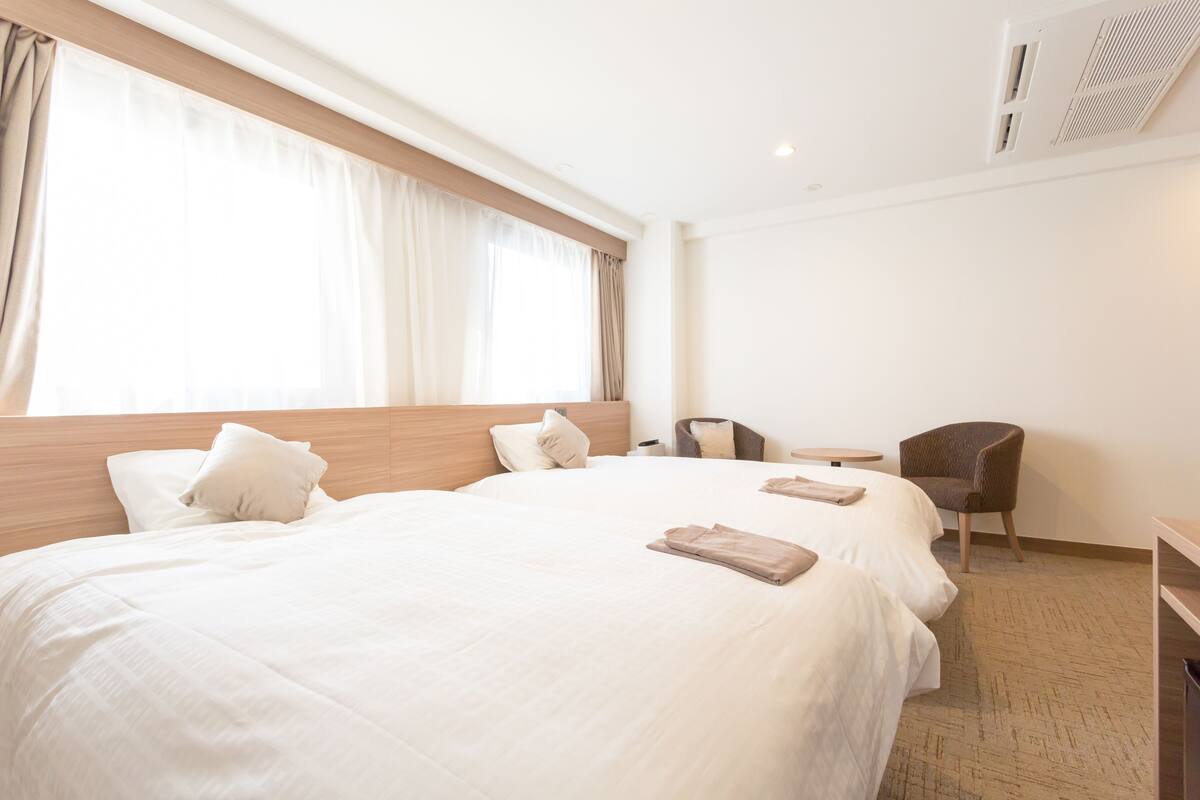 A hotel room with a large bed, a desk, and a chair.