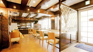A restaurant with wooden chairs and tables, a brick wall, and a large window. - Shimizu City Hotel (Shizuoka)