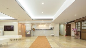 A modern hotel lobby with a reception desk, seating area, and a large skylight. - Shimizu City Hotel (Shizuoka)