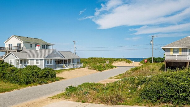 A coastal road leading to beachfront houses with a clear sky. - Too Close - KDH MP 6, Ocean Views, 65 Yards to Beach, Foosball, 2 Kitchens, Flex Stays (Kill Devil Hills)
